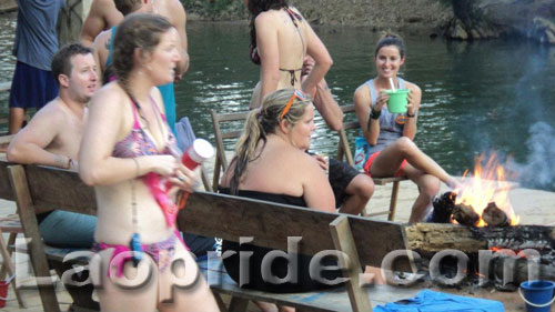 Tourists relax in front of a wood fire in Vang Vieng, Laos