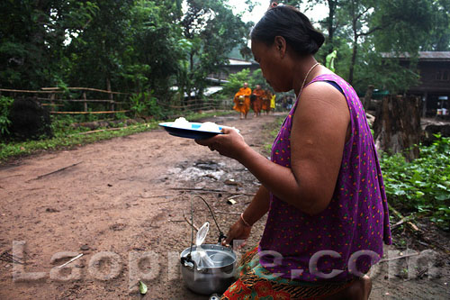 Elderly Lao woman offers food for monks